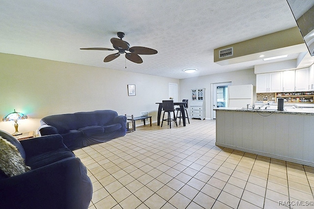 living room with ceiling fan, light tile patterned floors, and a textured ceiling