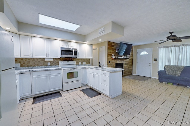 kitchen with light tile patterned floors, white appliances, white cabinetry, and sink