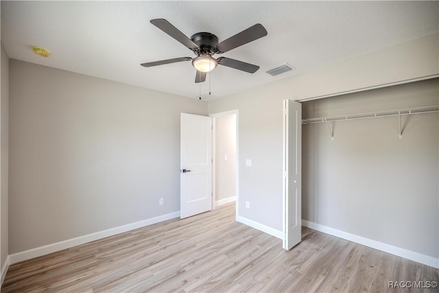unfurnished bedroom with wood finished floors, visible vents, baseboards, and a closet