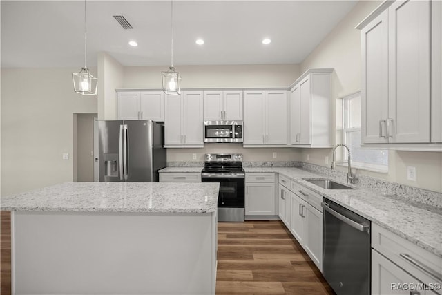 kitchen featuring stainless steel appliances, white cabinetry, sink, and pendant lighting