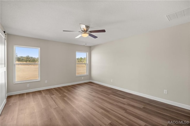 spare room with hardwood / wood-style floors, a textured ceiling, and ceiling fan