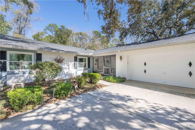 ranch-style home with an attached garage, a sunroom, and concrete driveway