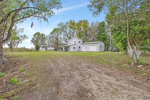 view of yard with an attached garage, dirt driveway, and fence