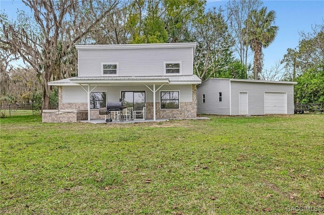 back of house featuring stone siding, a patio area, and a lawn