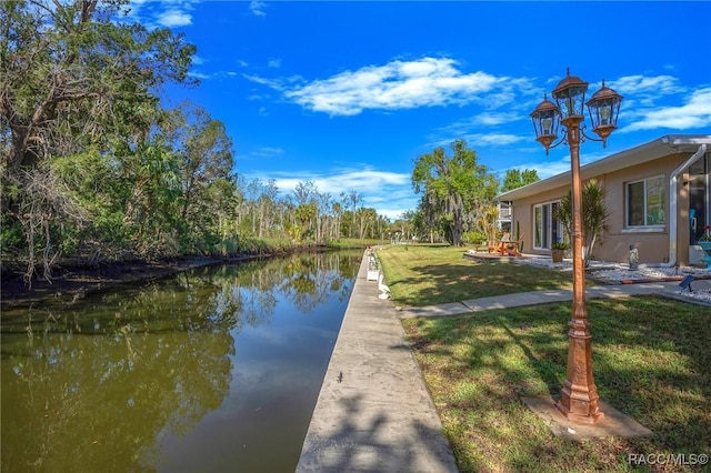 view of dock with a water view and a yard