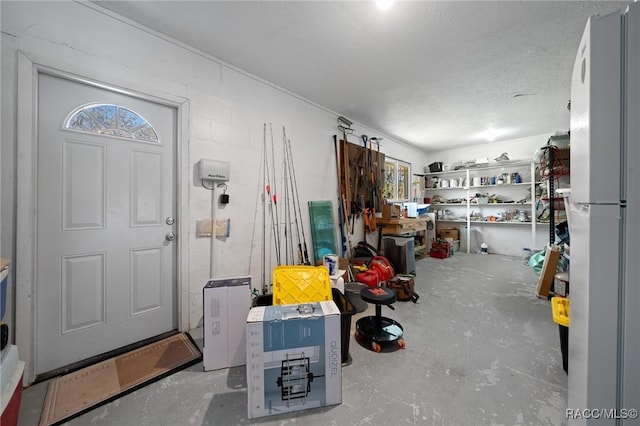 garage featuring concrete block wall and freestanding refrigerator