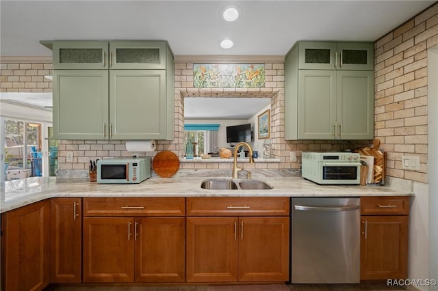 kitchen with a sink, green cabinetry, light stone counters, white microwave, and stainless steel dishwasher