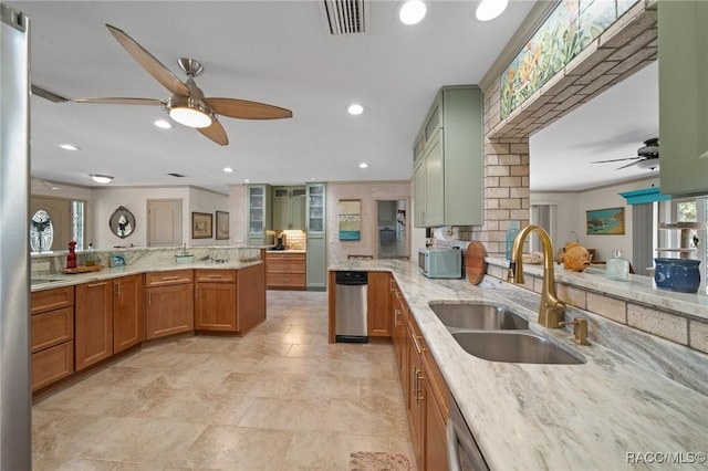 kitchen with a sink, light stone counters, visible vents, ceiling fan, and brown cabinets