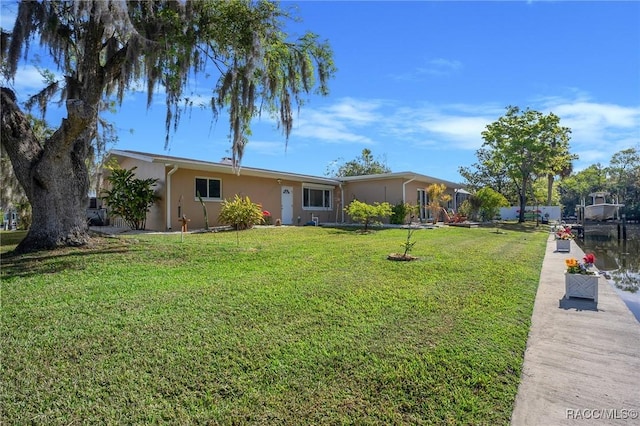 ranch-style house with a front lawn, stucco siding, and a boat dock