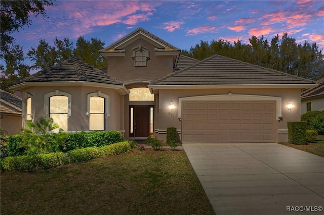 view of front of home featuring a garage, concrete driveway, a tile roof, and stucco siding