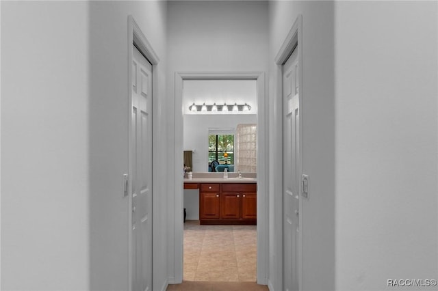 hallway with light tile patterned floors and a sink