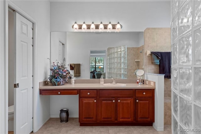 ensuite bathroom with tile patterned flooring, connected bathroom, vanity, and walk in shower