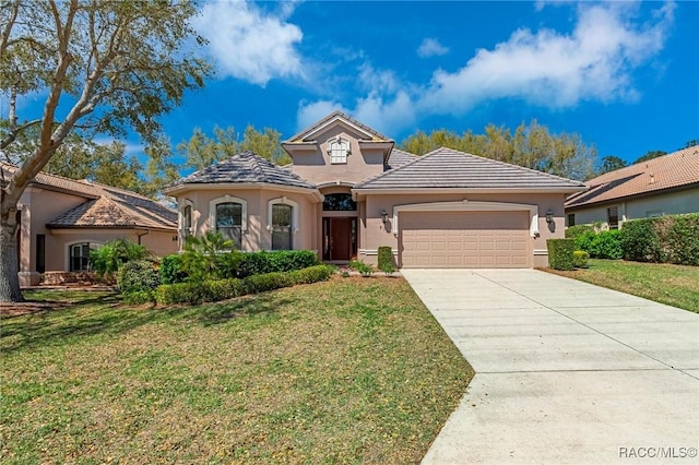 mediterranean / spanish home featuring a front lawn, an attached garage, and stucco siding