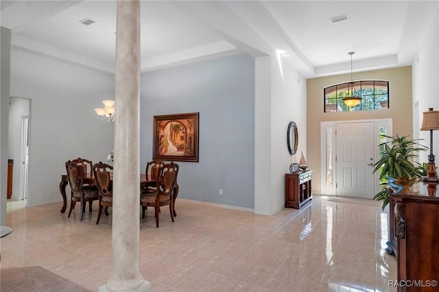 foyer featuring a tray ceiling, a high ceiling, visible vents, and baseboards