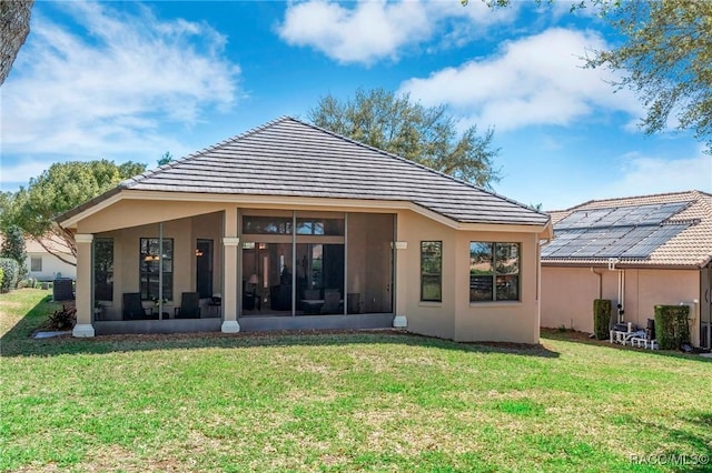 rear view of property featuring a sunroom, cooling unit, a lawn, and a tiled roof