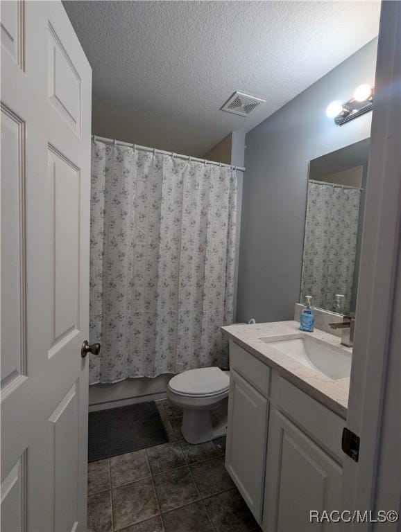 bathroom with vanity, toilet, and a textured ceiling