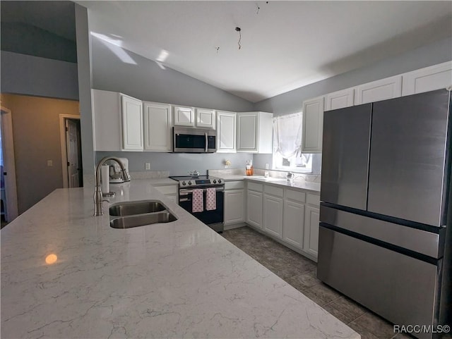 kitchen featuring white cabinetry, lofted ceiling, sink, light stone counters, and stainless steel appliances