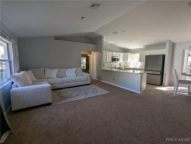 unfurnished living room featuring sink, carpet floors, and vaulted ceiling