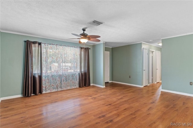 unfurnished room with wood-type flooring, crown molding, and a textured ceiling