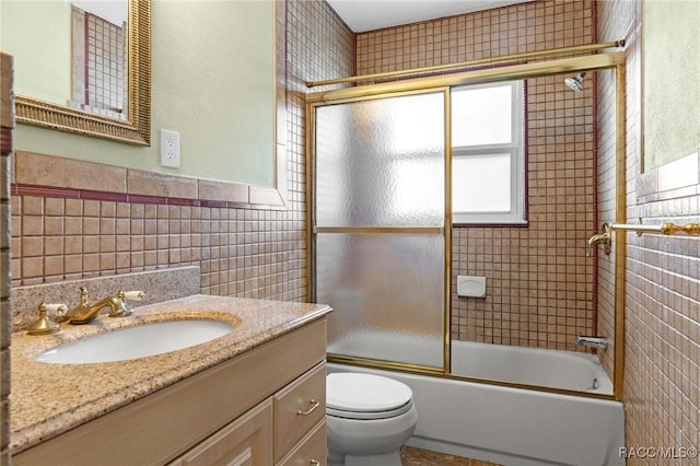 full bathroom featuring tile walls, vanity, enclosed tub / shower combo, and toilet