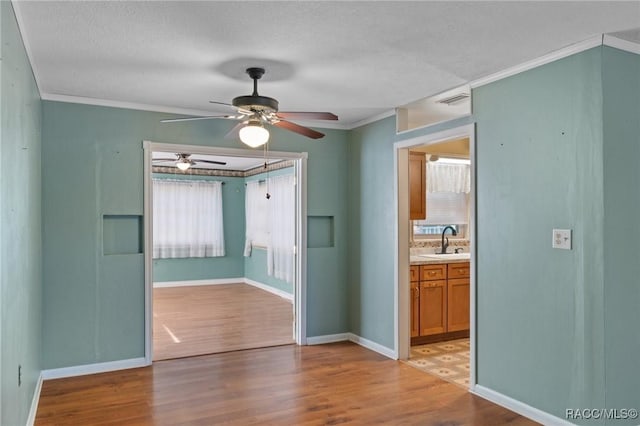 spare room featuring ornamental molding, sink, a textured ceiling, and light hardwood / wood-style floors