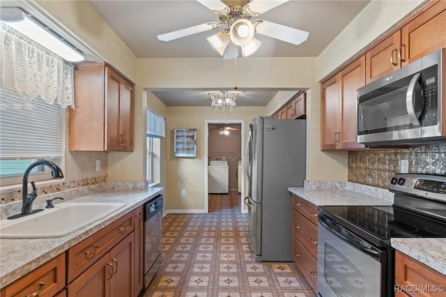 kitchen featuring washer / dryer, sink, stainless steel appliances, ceiling fan with notable chandelier, and backsplash