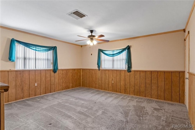 spare room with a healthy amount of sunlight, wood walls, and carpet flooring