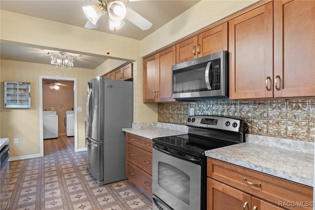 kitchen with tasteful backsplash, ceiling fan with notable chandelier, washer and clothes dryer, and stainless steel appliances