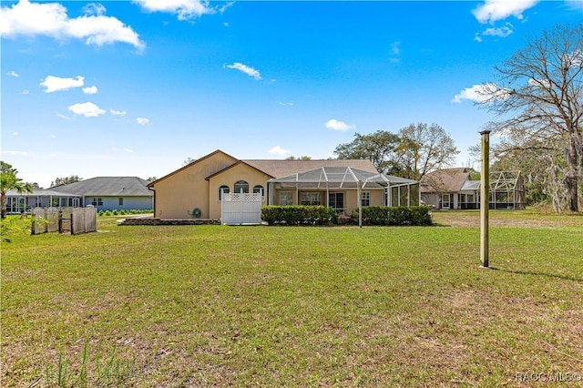 view of front of home with glass enclosure, fence, a front lawn, and stucco siding