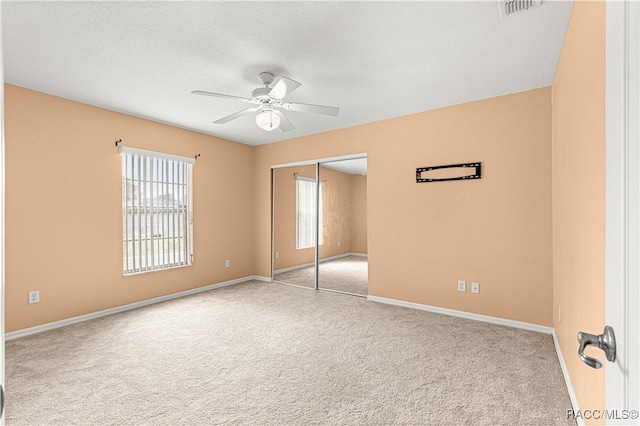 unfurnished bedroom with a textured ceiling, a ceiling fan, baseboards, a closet, and carpet