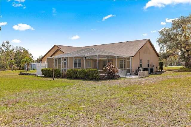 back of property with a lanai, stucco siding, and a yard