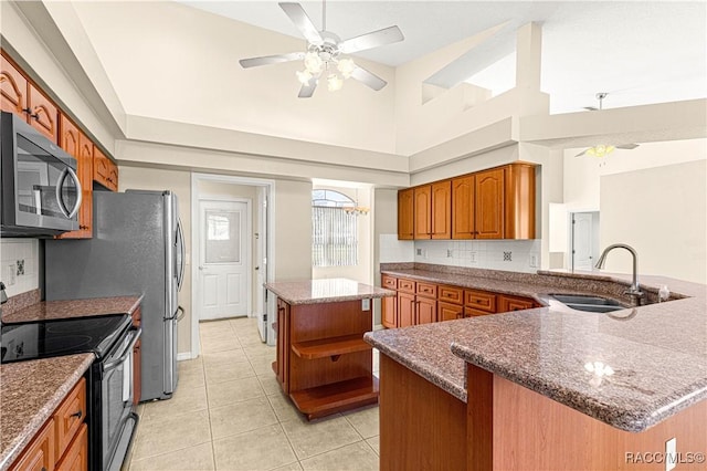 kitchen featuring brown cabinets, stainless steel microwave, black range with electric stovetop, light tile patterned flooring, and a sink