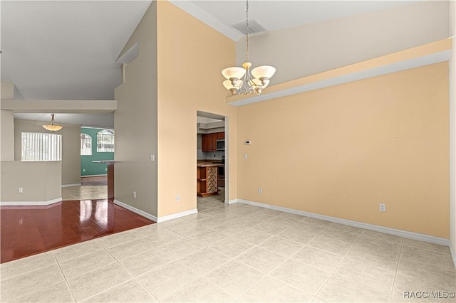 tiled spare room with high vaulted ceiling, visible vents, a notable chandelier, and baseboards