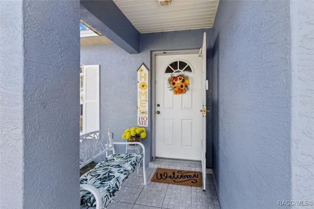 doorway to property featuring stucco siding