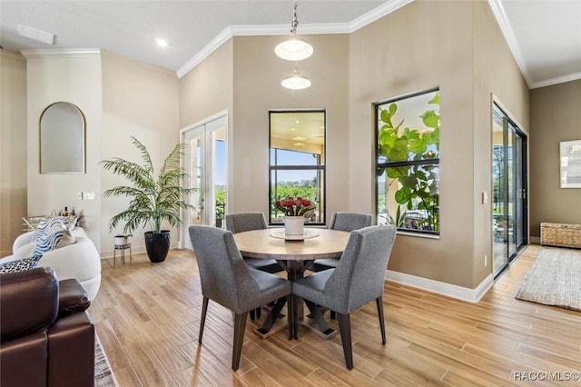 dining room featuring visible vents, baseboards, ornamental molding, french doors, and light wood finished floors