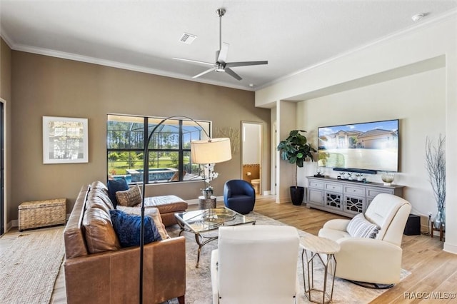 living room featuring ceiling fan, light wood-style flooring, visible vents, baseboards, and ornamental molding