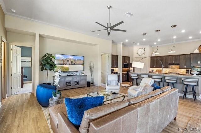 living area with light wood finished floors, visible vents, ceiling fan, crown molding, and recessed lighting