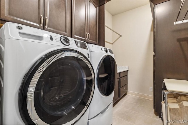 washroom with cabinet space, washer and clothes dryer, baseboards, and light tile patterned flooring