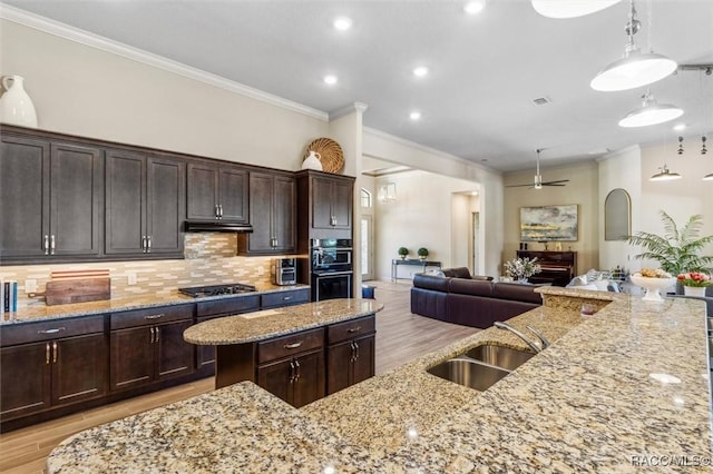 kitchen with light wood-type flooring, backsplash, open floor plan, and a sink