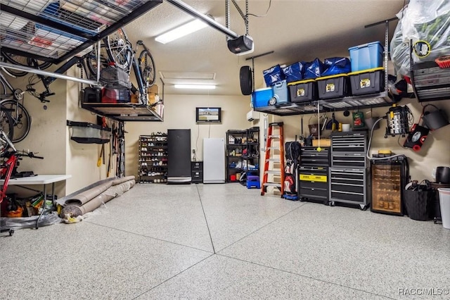 garage with a workshop area, freestanding refrigerator, and a garage door opener