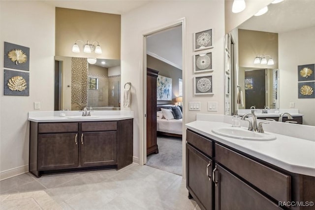 bathroom with tiled shower, two vanities, a sink, and baseboards