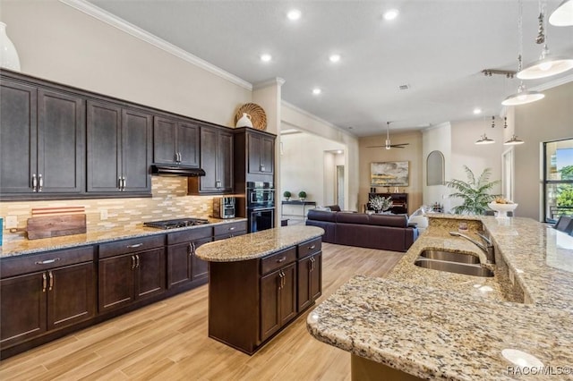 kitchen featuring a sink, open floor plan, backsplash, a center island, and crown molding