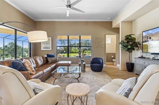 living area with ornamental molding, light wood-style floors, and a healthy amount of sunlight