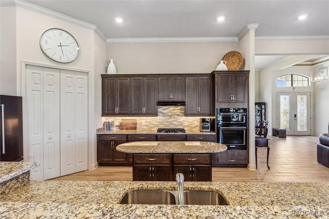 kitchen featuring dark brown cabinetry, stainless steel gas cooktop, a sink, and refrigerator