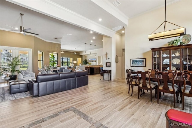 living area with ornamental molding, visible vents, light wood-style flooring, and a ceiling fan