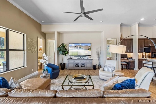 living room with a healthy amount of sunlight, crown molding, and light wood finished floors