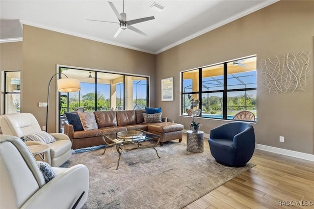 living room with a ceiling fan, wood finished floors, visible vents, and crown molding