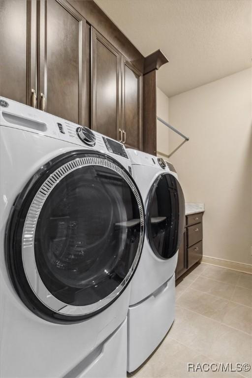 clothes washing area featuring cabinet space, baseboards, separate washer and dryer, and light tile patterned flooring