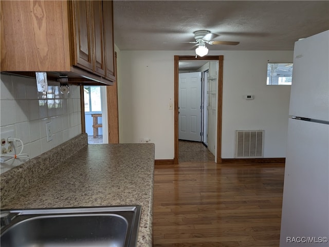 kitchen featuring decorative backsplash, a textured ceiling, ceiling fan, white fridge, and dark hardwood / wood-style floors