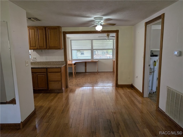 kitchen featuring backsplash, ceiling fan, a textured ceiling, water heater, and wood-type flooring